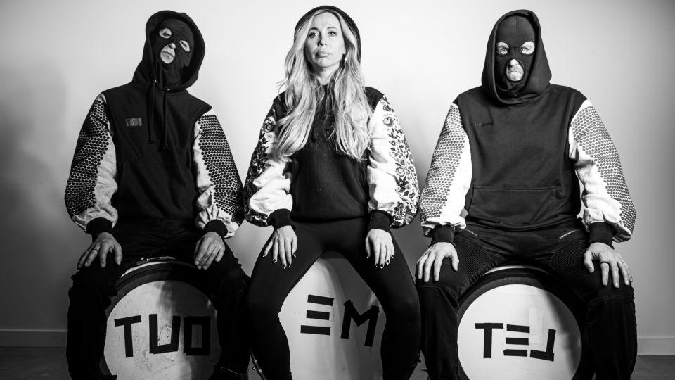 black and white photo of three musicians sitting on drums that say Let Me Out